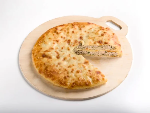 Осетинский пирог с курицей и картошкой — разрез с начинкой на деревянной доске